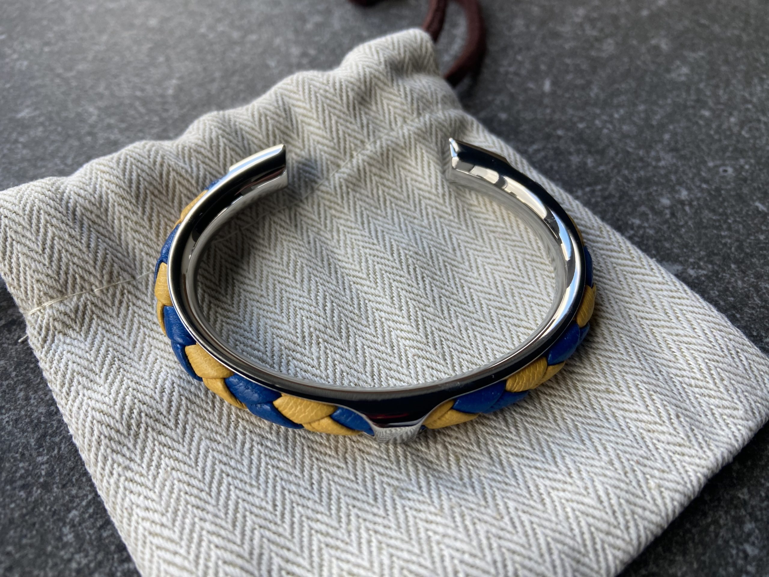 Yellow and blue spiral braided leather cuff bracelet with folded edges, stainless steel setting.