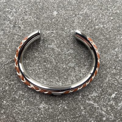 Tan and ivory braided leather cuff bracelet in polished stainless steel.