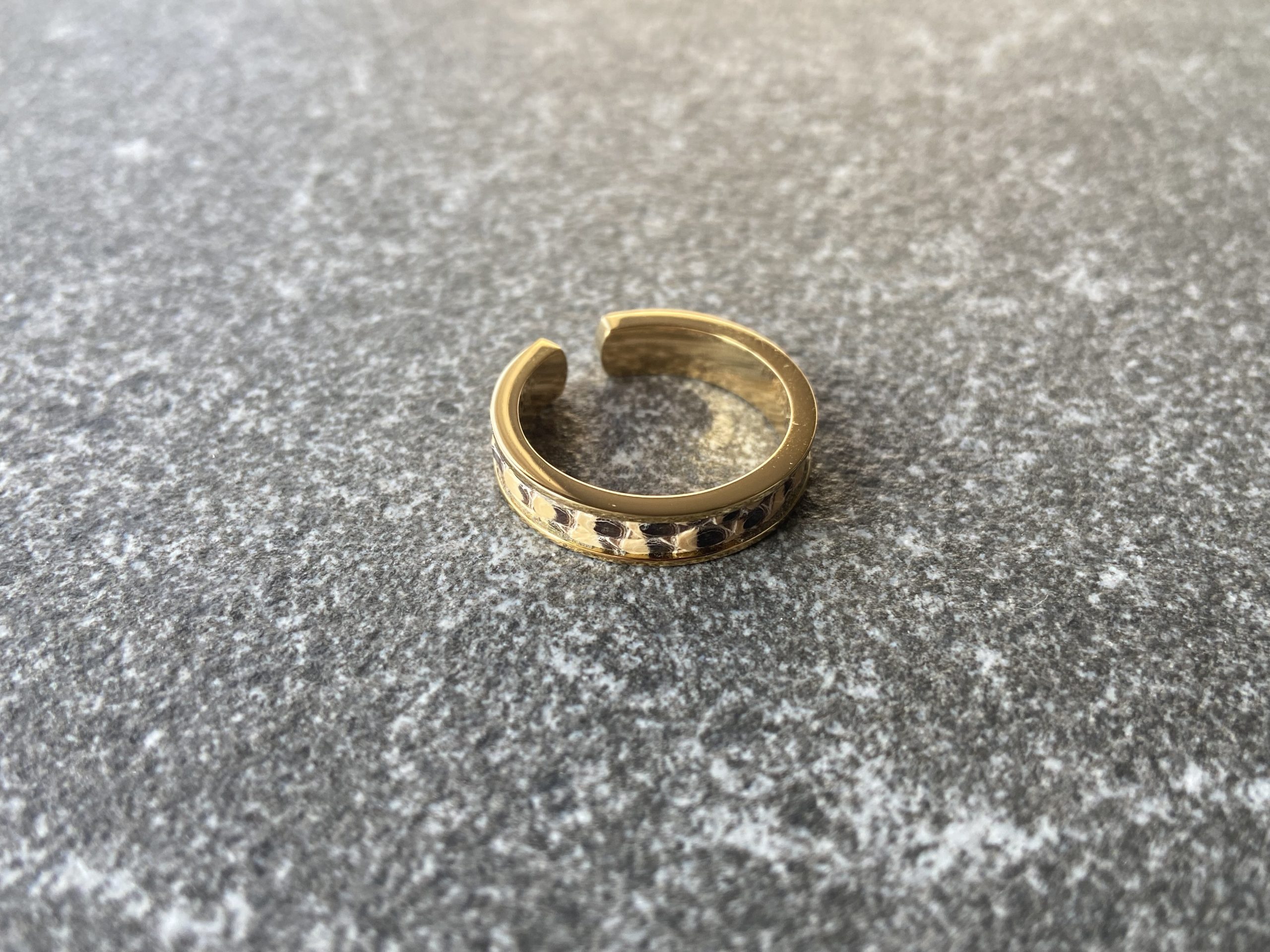 Gold-plated stainless steel ring with Sand Scale Line leather inlay on a grey stone background