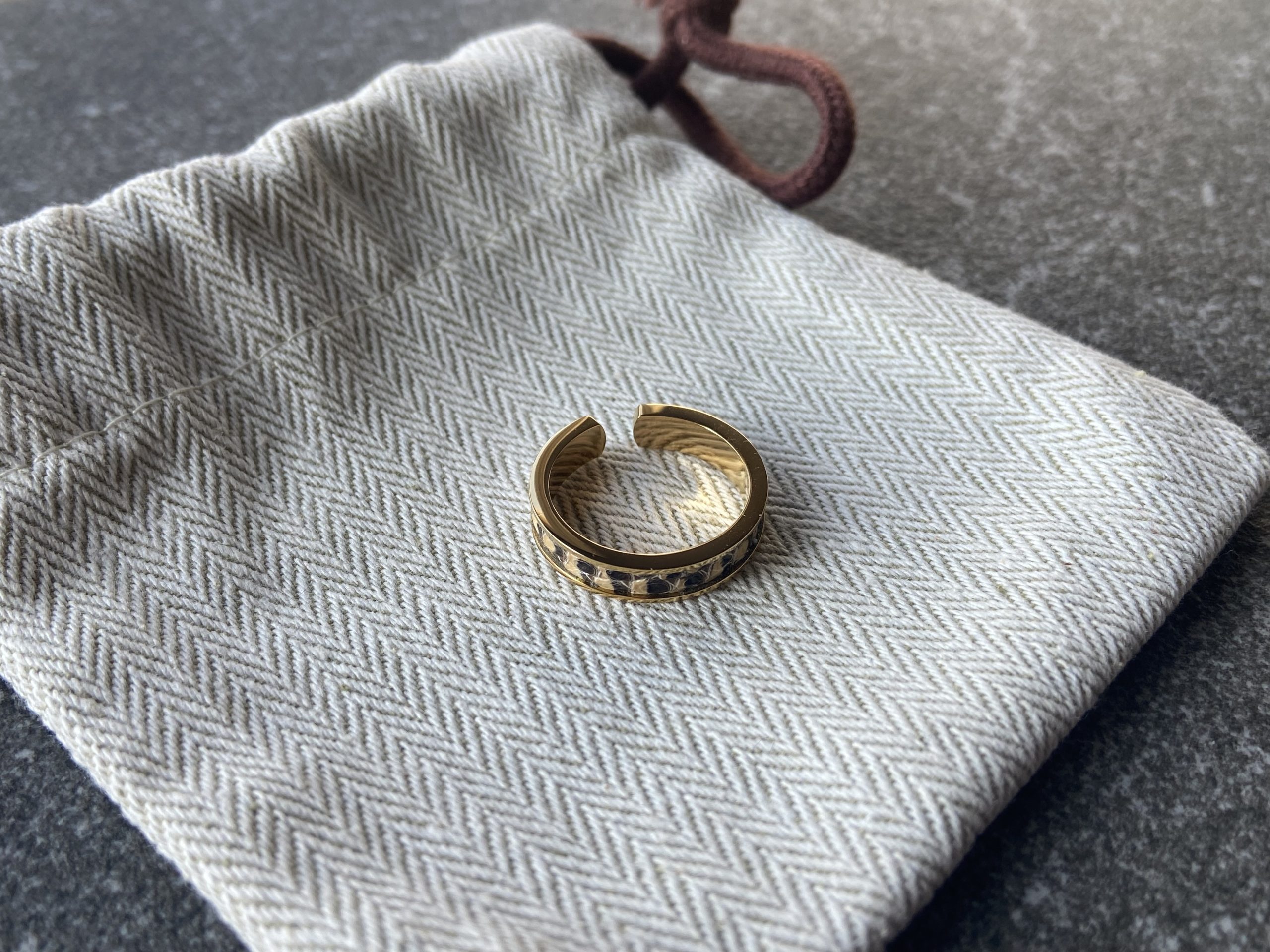 Gold-plated stainless steel ring with Sand Scale Line leather inlay on cotton herringbone pouch