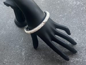 White leather braided cuff bracelet in polished stainless steel.