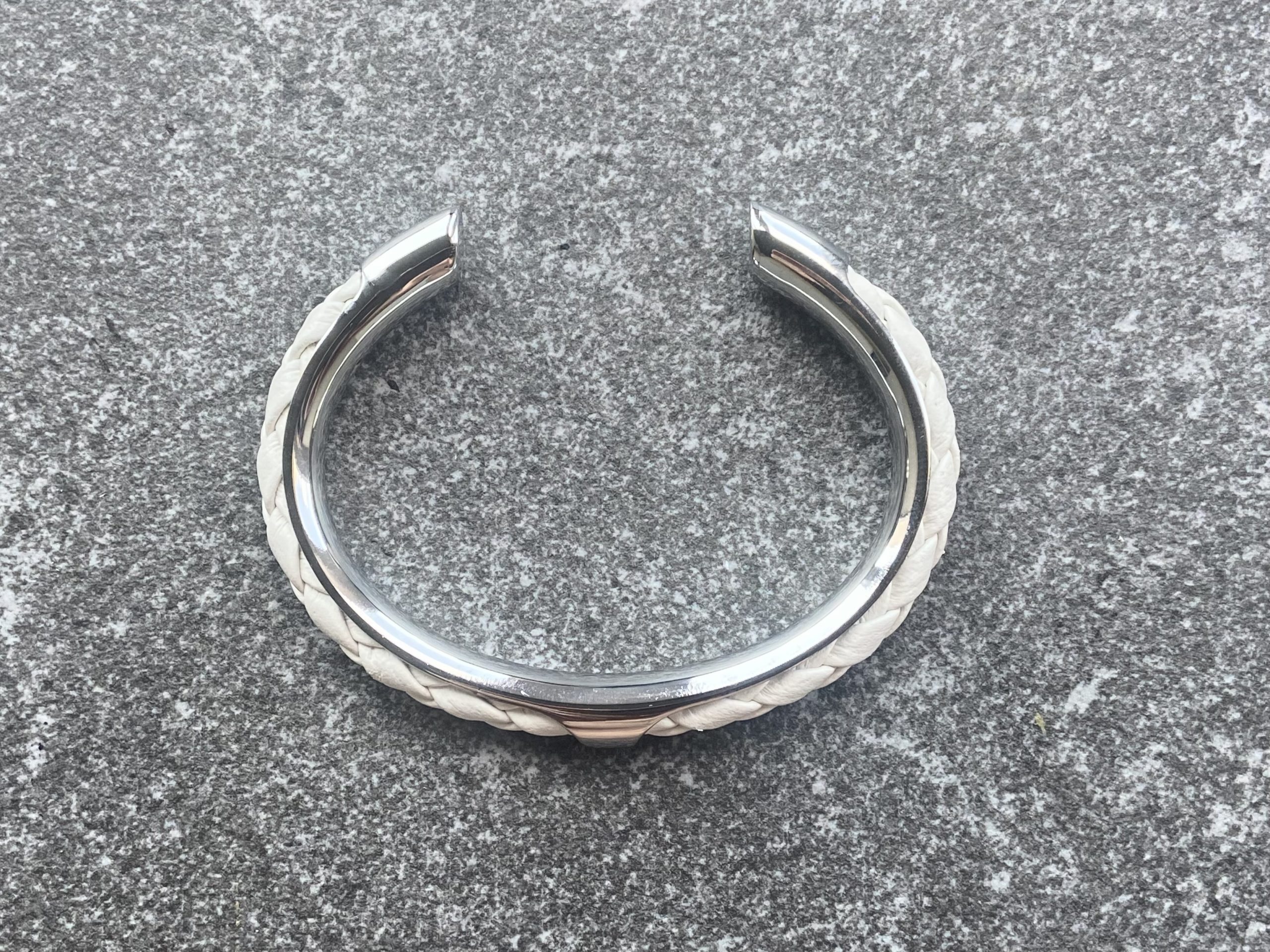 White leather braided cuff bracelet in polished stainless steel.