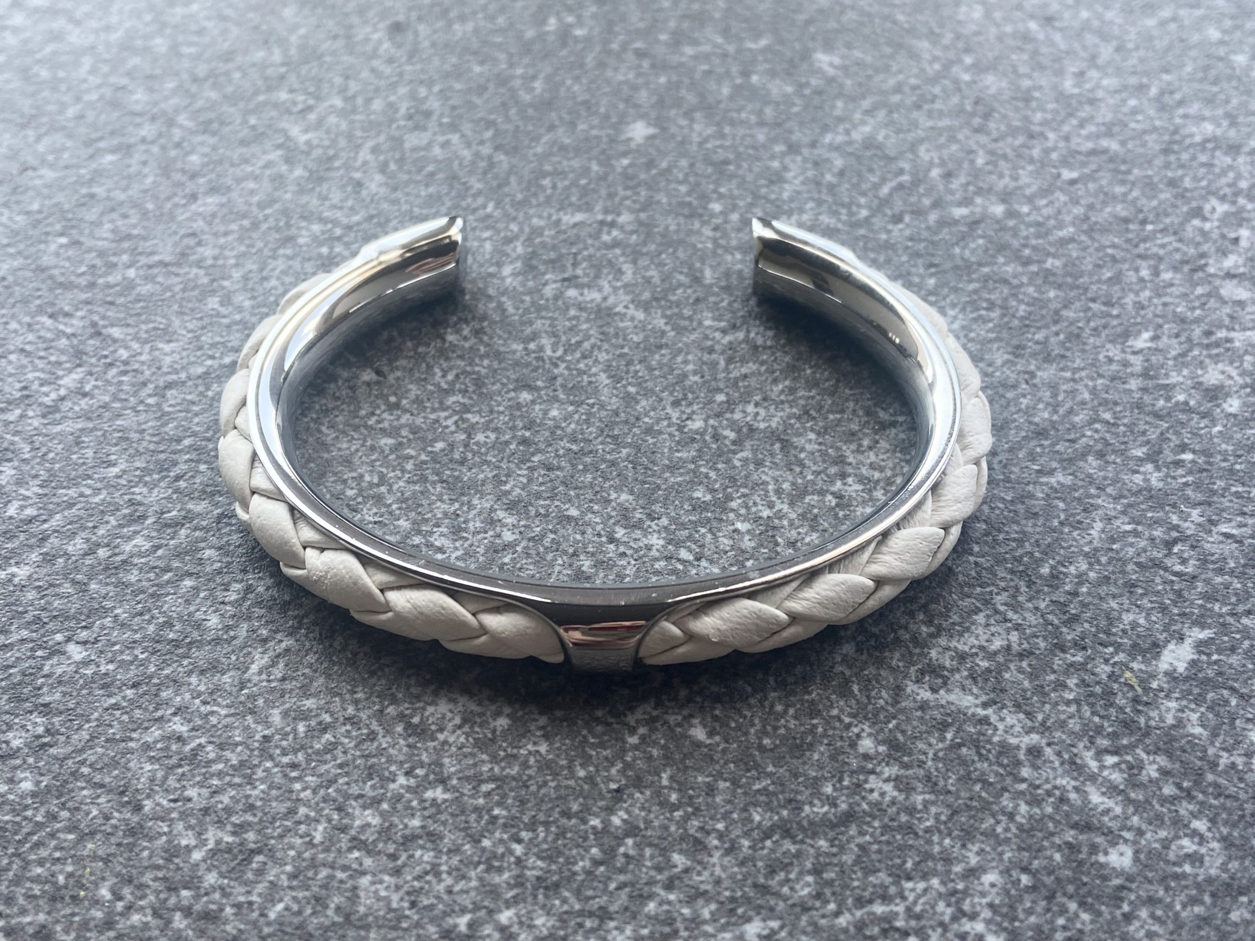 White leather braided cuff bracelet in polished stainless steel.