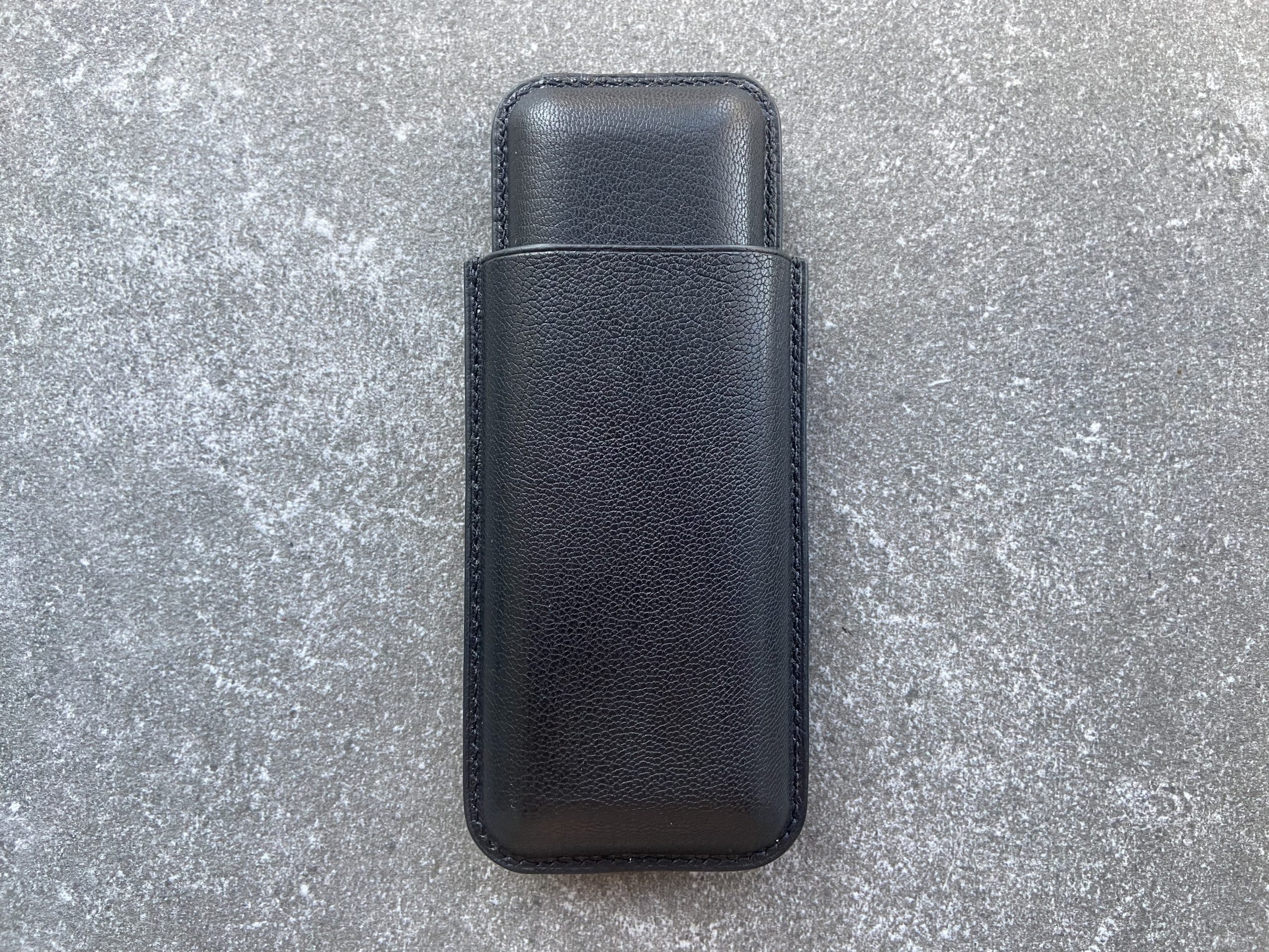 Leather cigar case in black leather on a stone surface