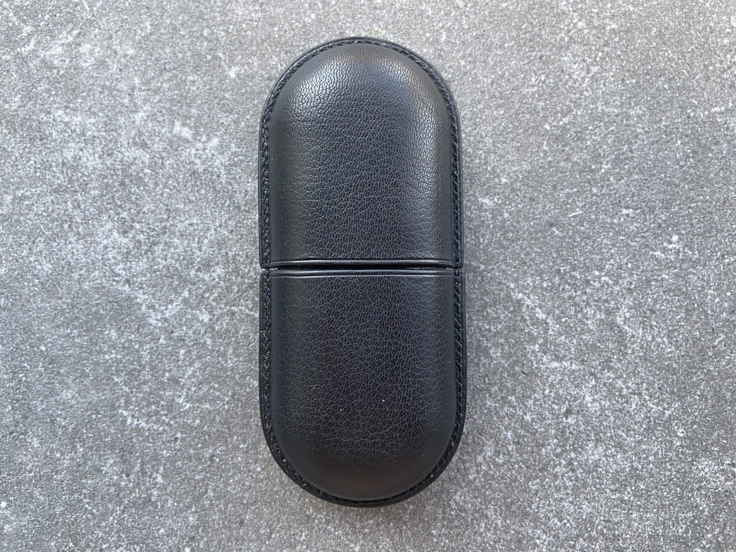 Leather glasses case with sliding lid in black leather, closed, on a stone surface