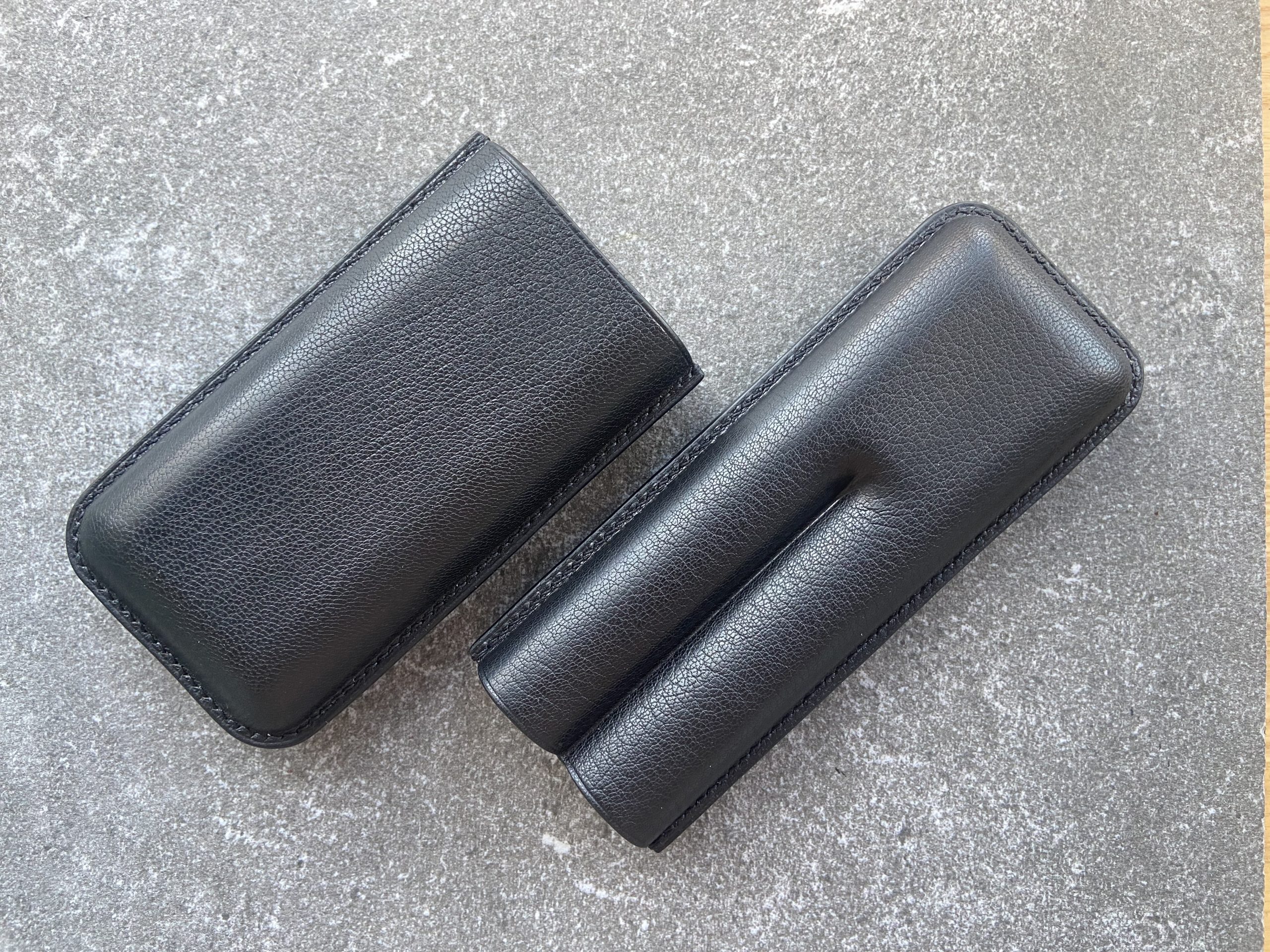 Leather cigar case in black leather shown closed and open on a stone surface