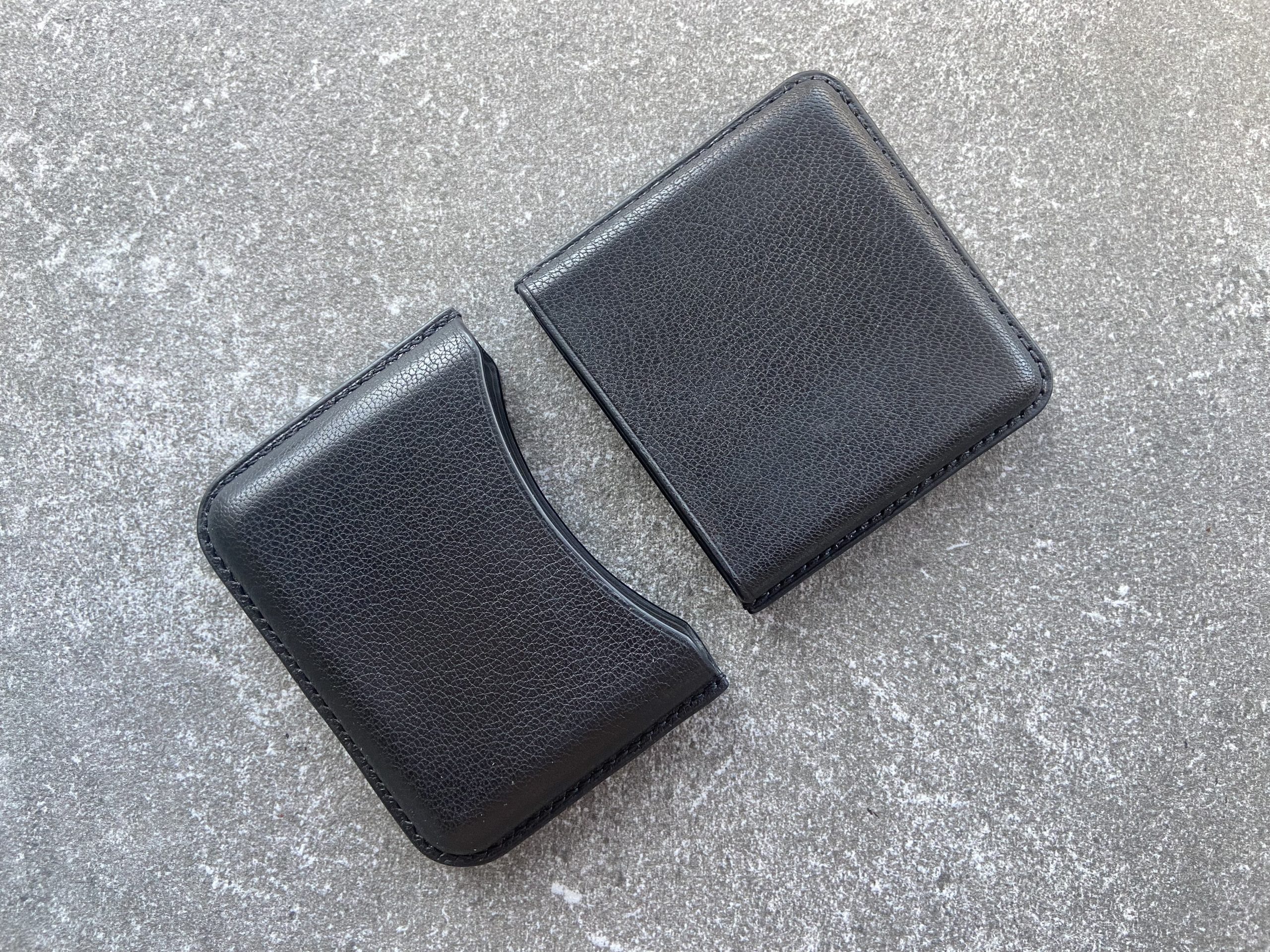 Leather cigarette case in black leather shown in two separate parts on a stone surface