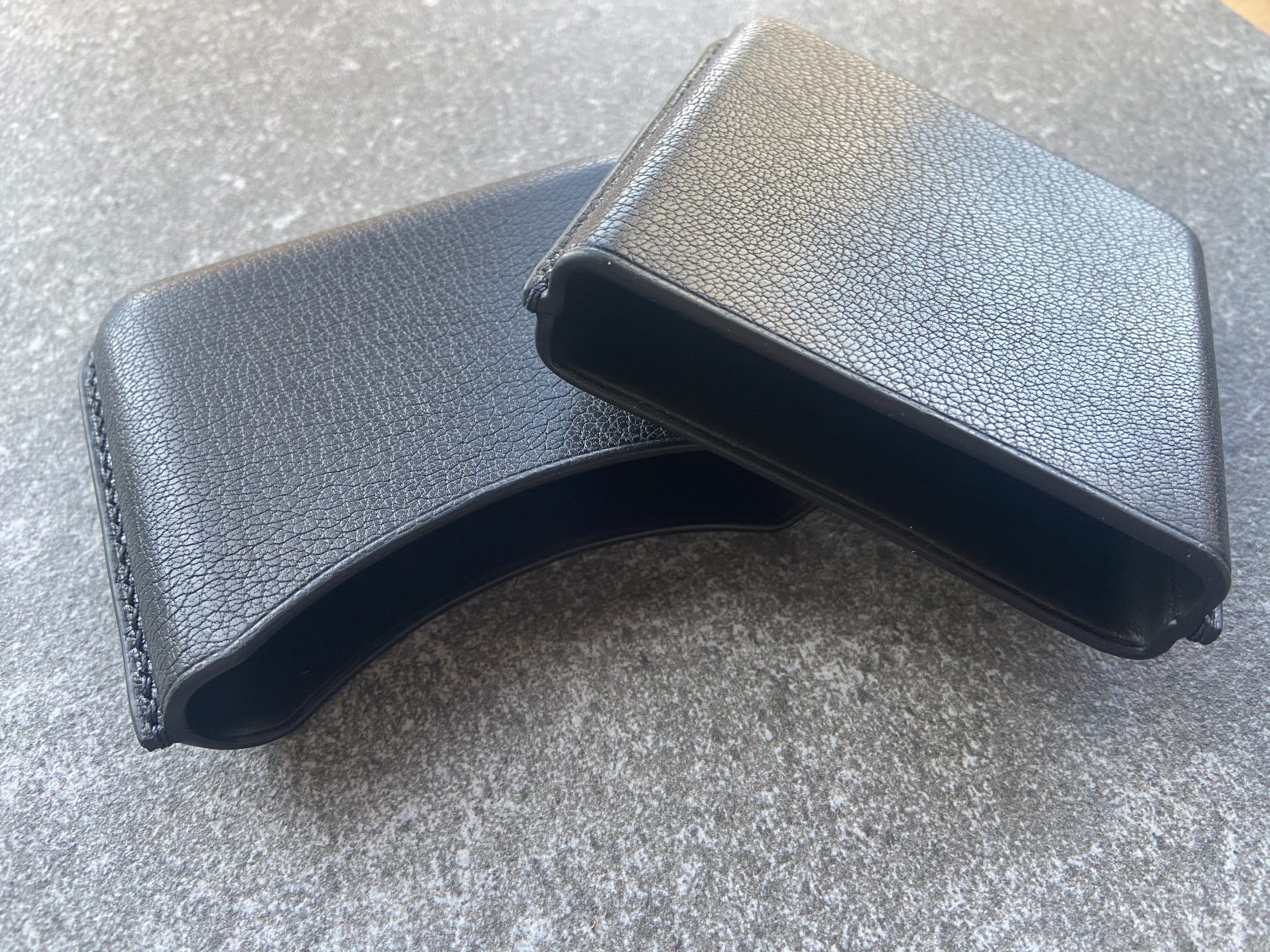 Leather cigarette case in black leather shown open with two separate parts on a stone surface