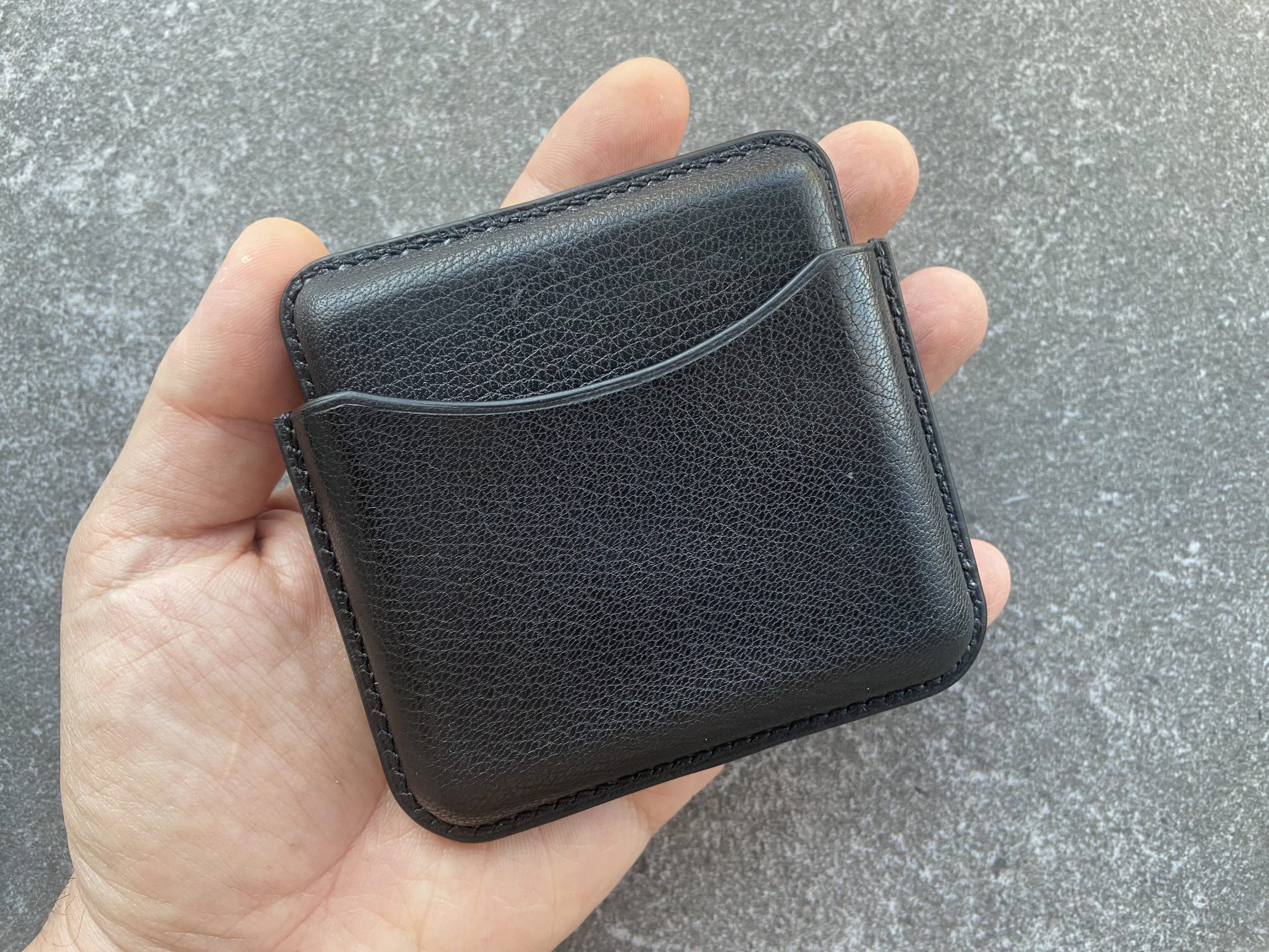Leather cigarette case in black leather held in hand on a stone surface