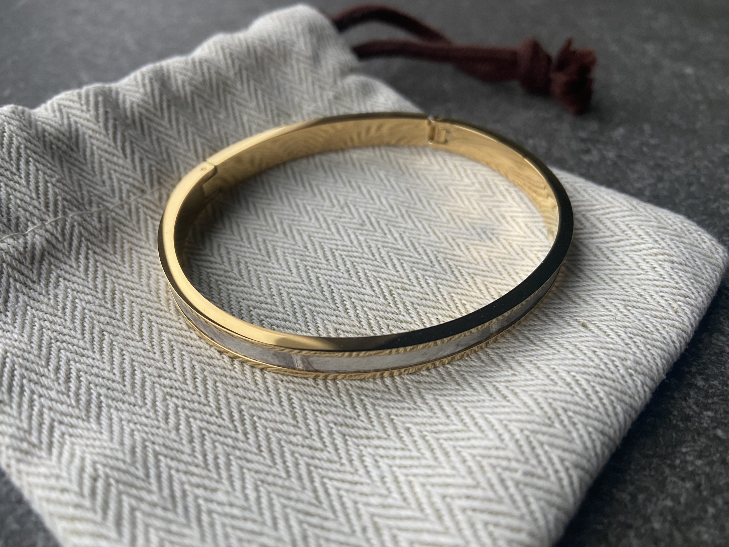 Gold-plated stainless steel clic bracelet with Himalaya leather inlay on herringbone pouch