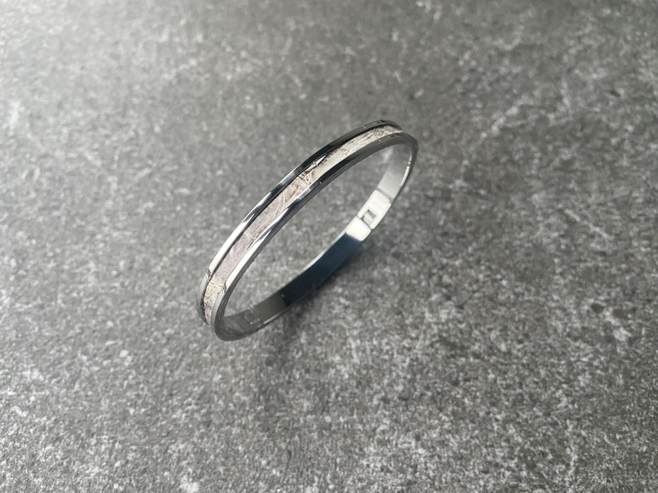 Stainless steel clic bracelet with Himalaya leather inlay on a grey stone background
