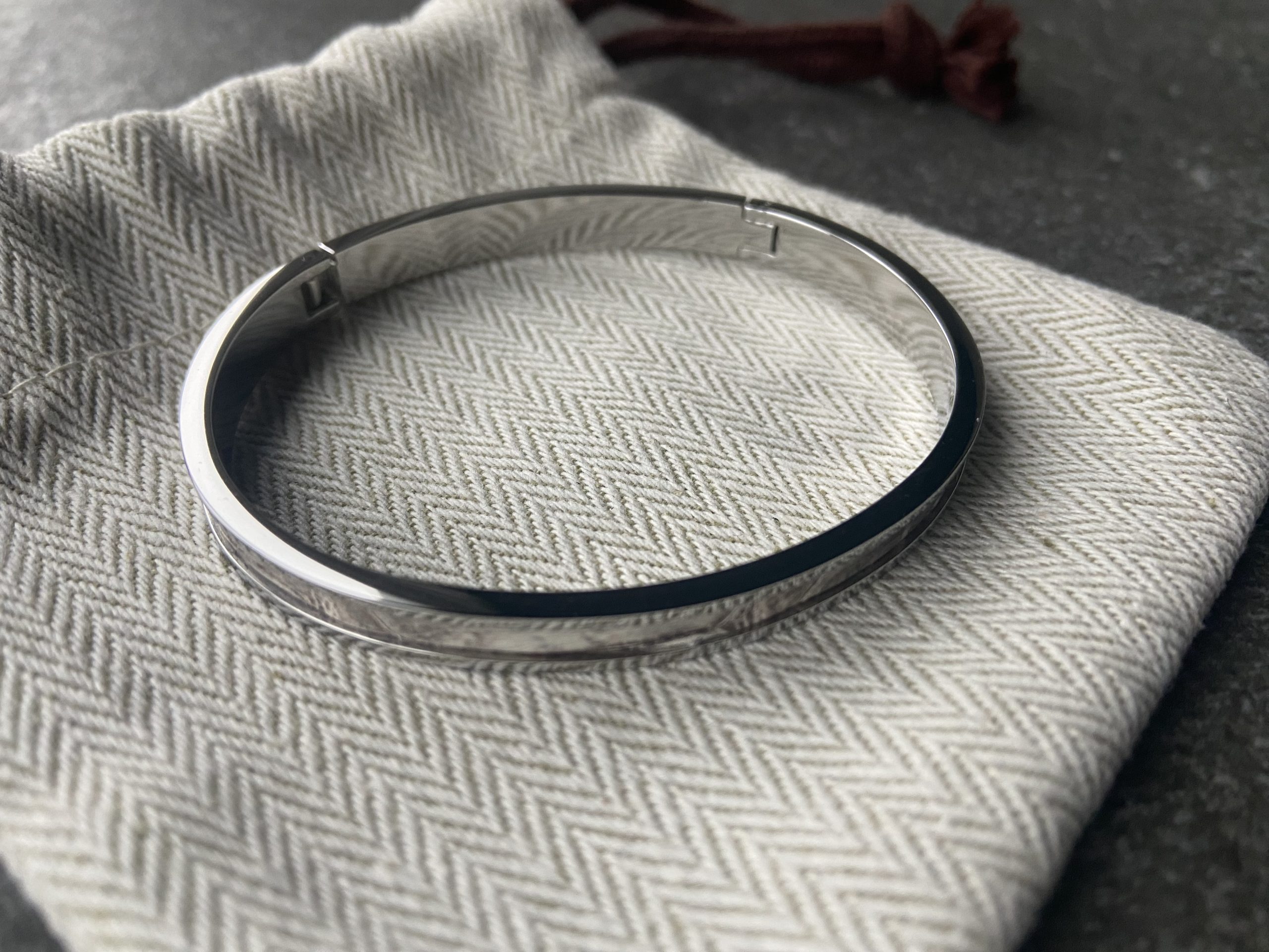 Stainless steel clic bracelet on a herringbone fabric pouch, inner side view