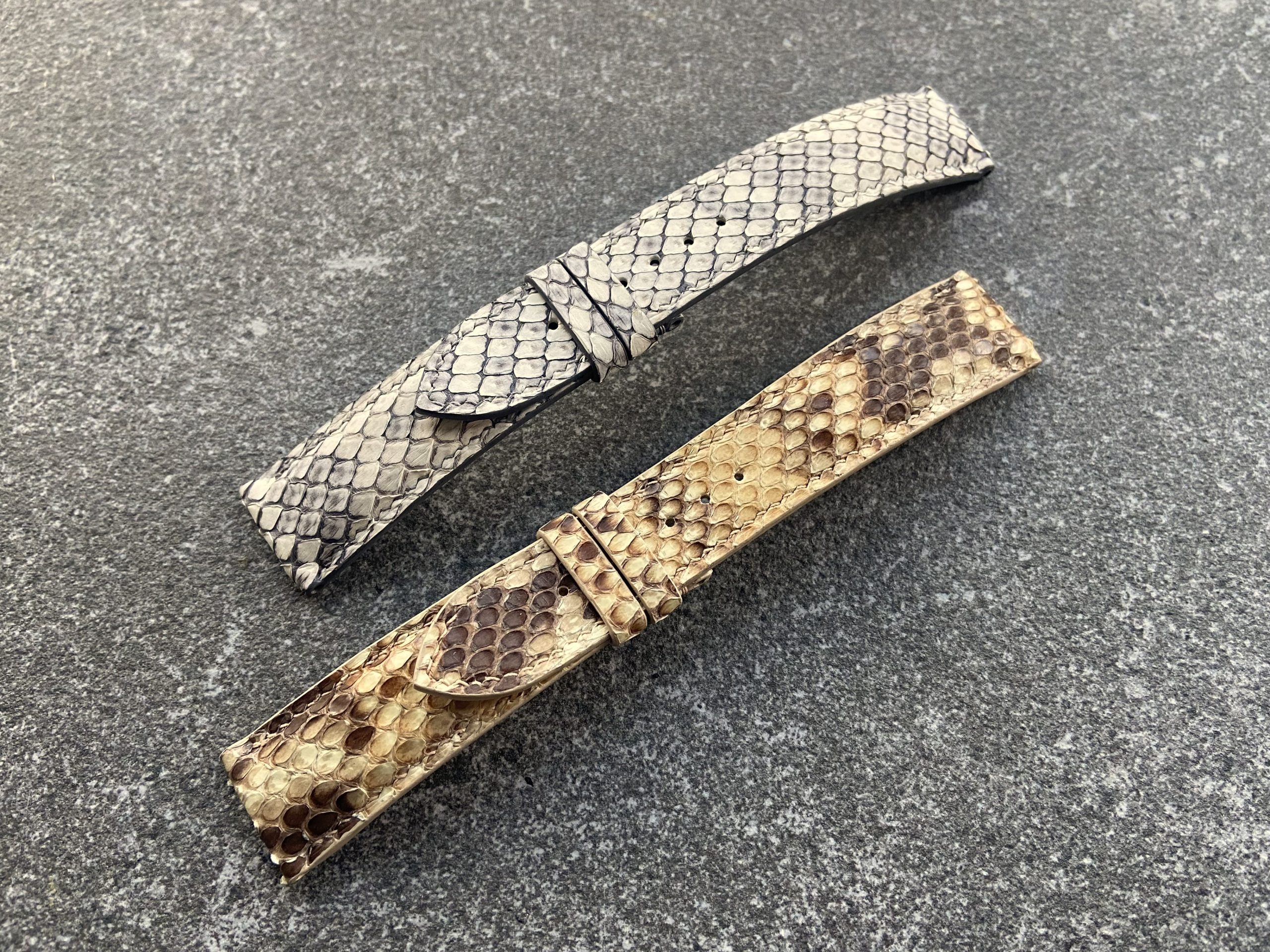 Two handcrafted python skin watch straps, one light grey and one brown.