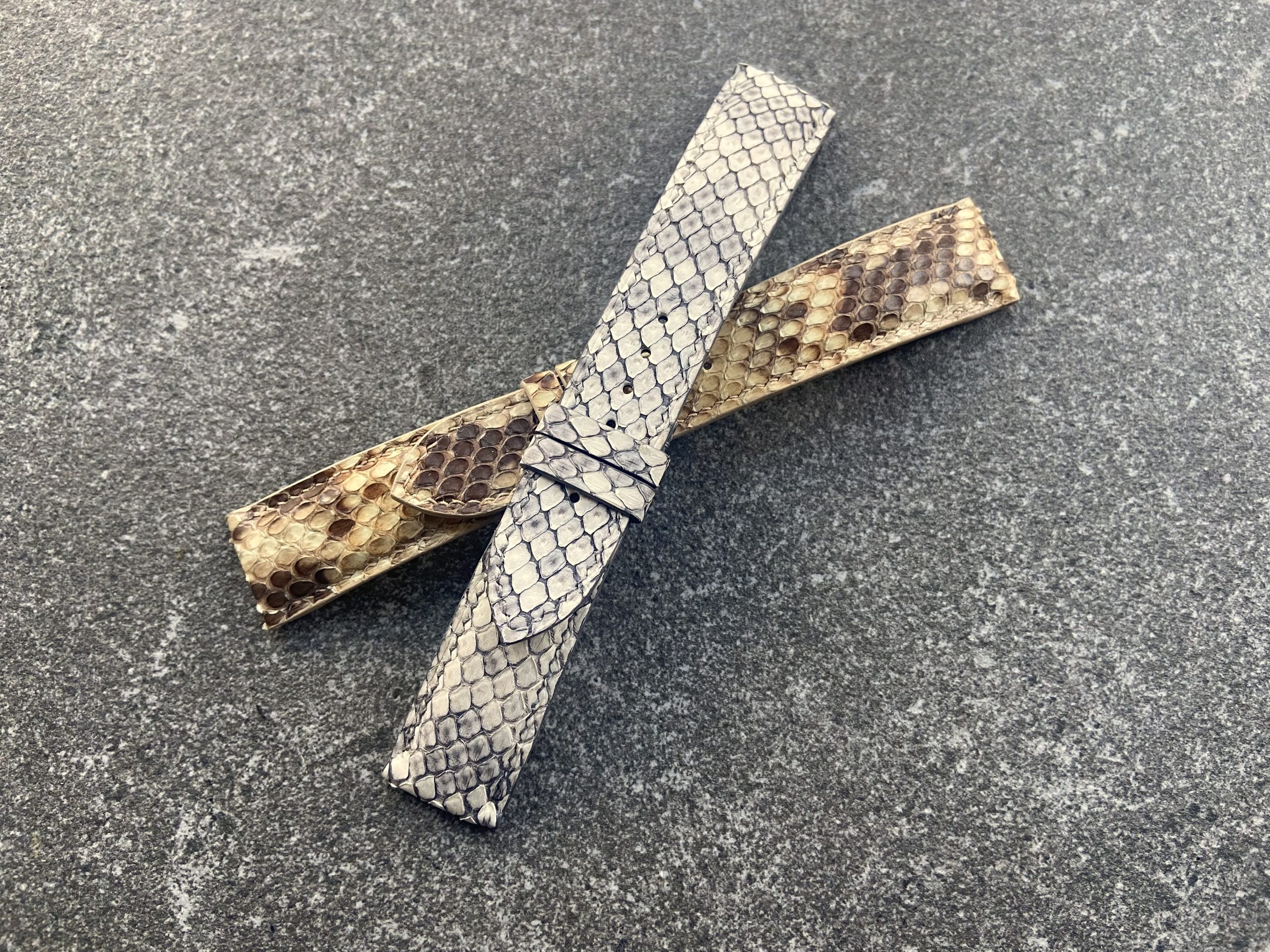 Two handcrafted python skin watch straps, one light grey and one brown.