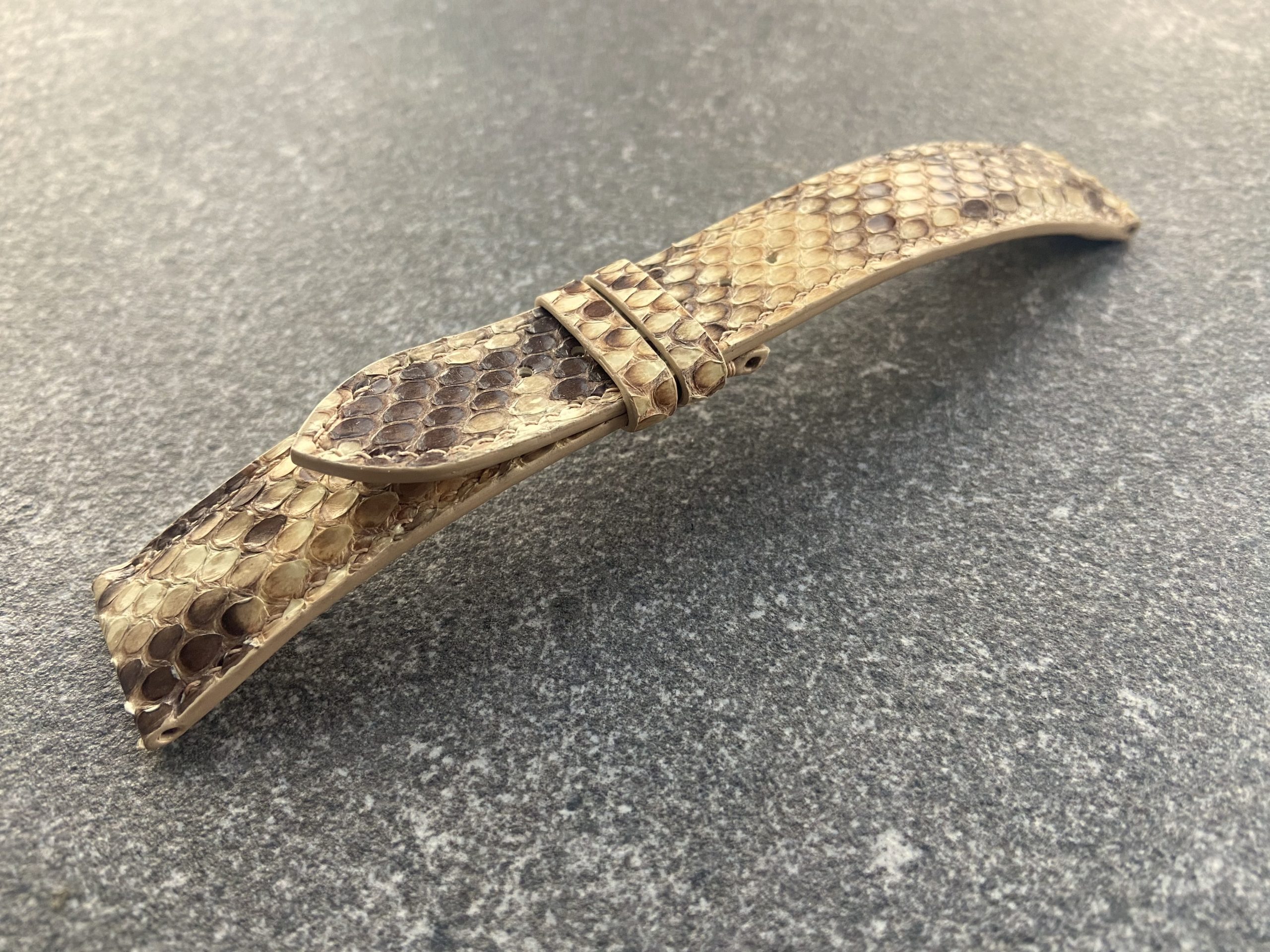 Python skin texture detail on a brown watch strap.