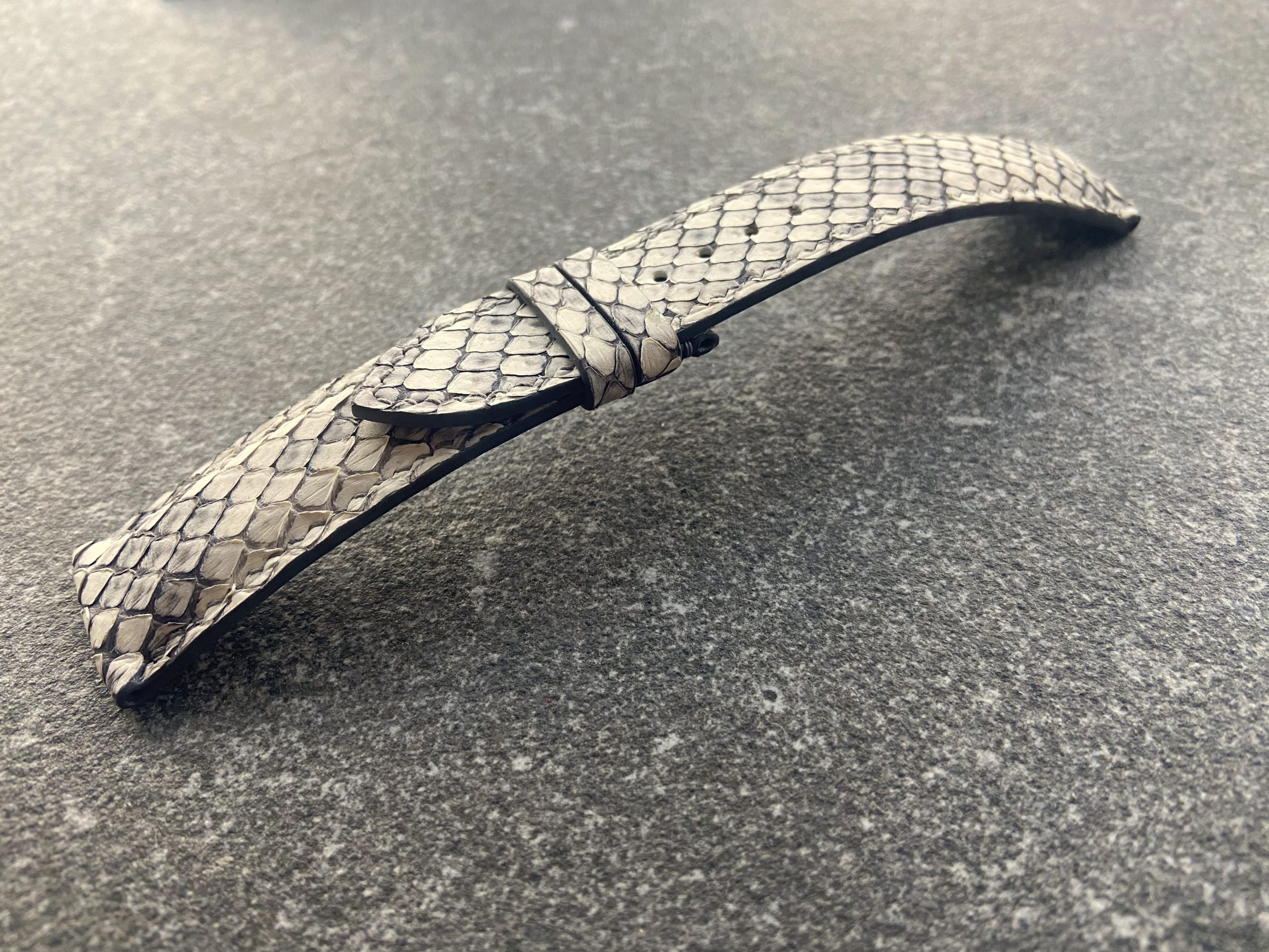 Close-up of light grey python skin texture on a watch strap.