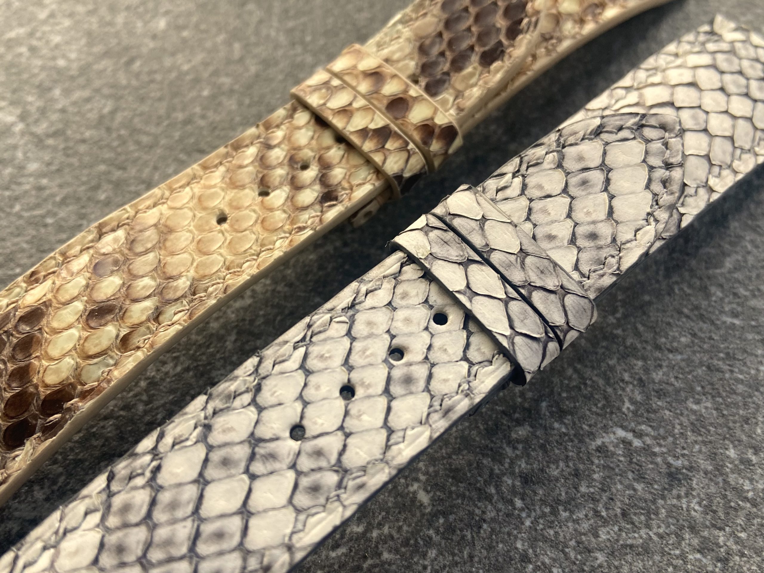 Two handcrafted python skin watch straps, one light grey and one brown.