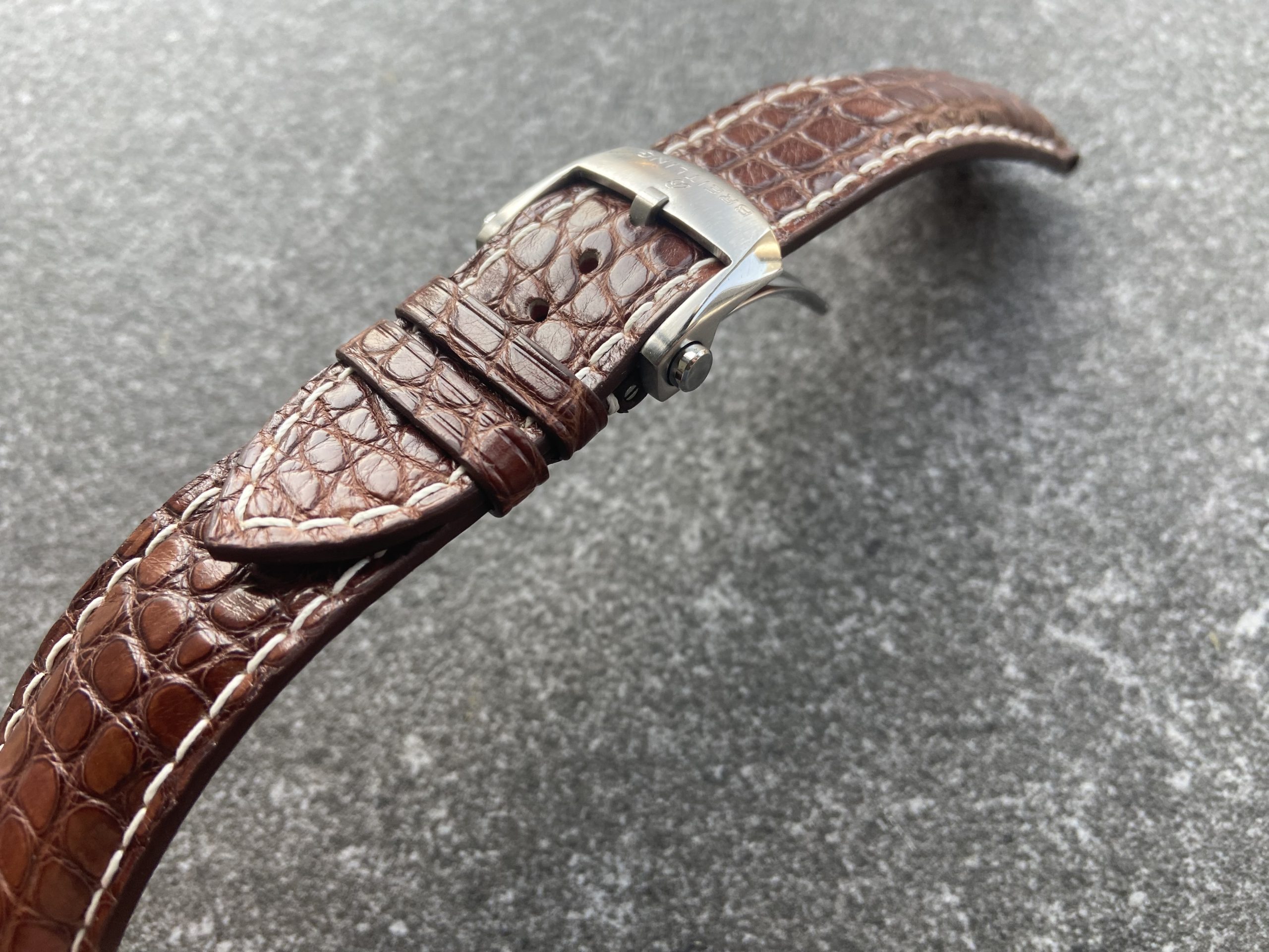 Close-up of cognac alligator leather strap with white stitching and Breitling clasp