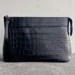 Pochette Voyage Souple in black alligator leather, handcrafted with saddle stitching and NFC tag