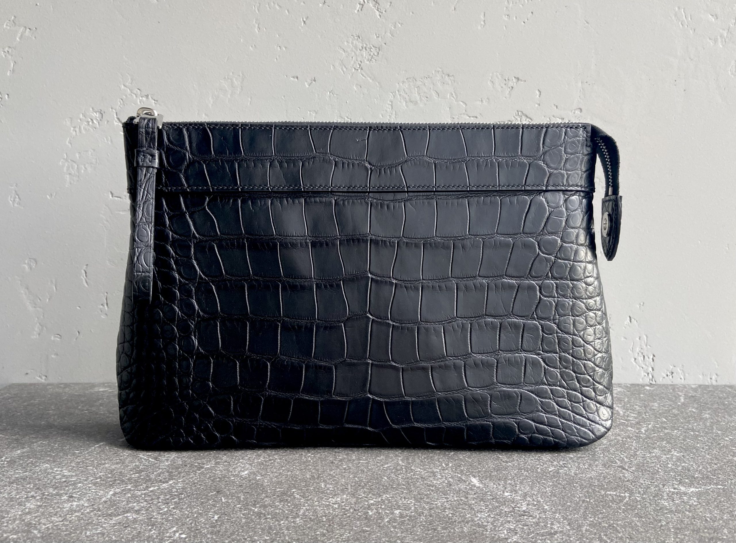 Pochette Voyage Souple in black alligator leather, handcrafted with saddle stitching and NFC tag