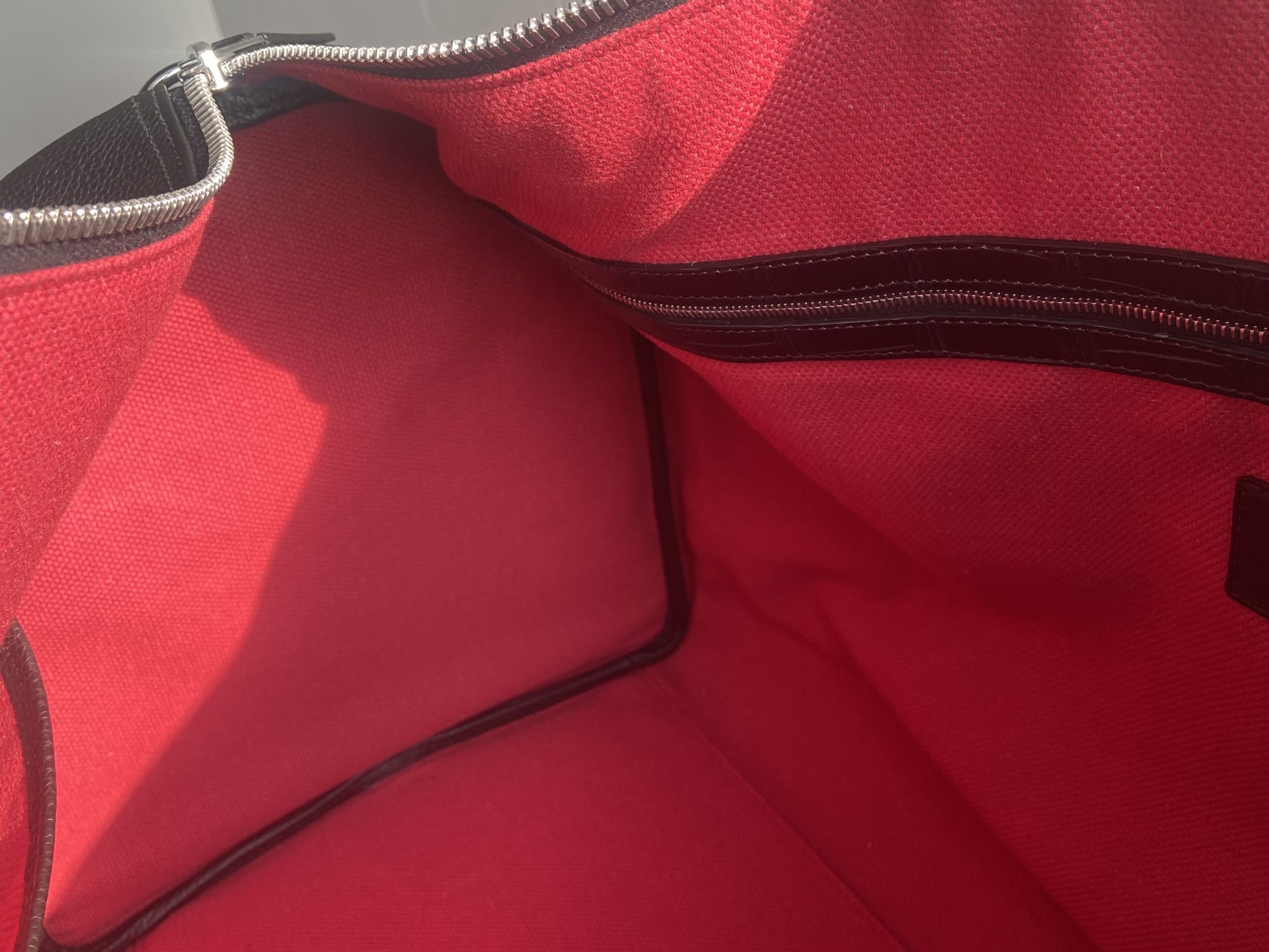 Interior view of the bespoke travel bag showing red Oscar lining and zip pocket with alligator leather frame