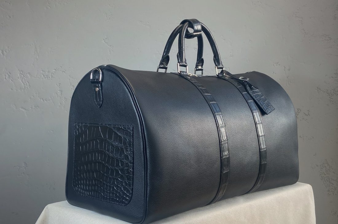 Side view of the bespoke travel bag in black calfskin and matte alligator leather