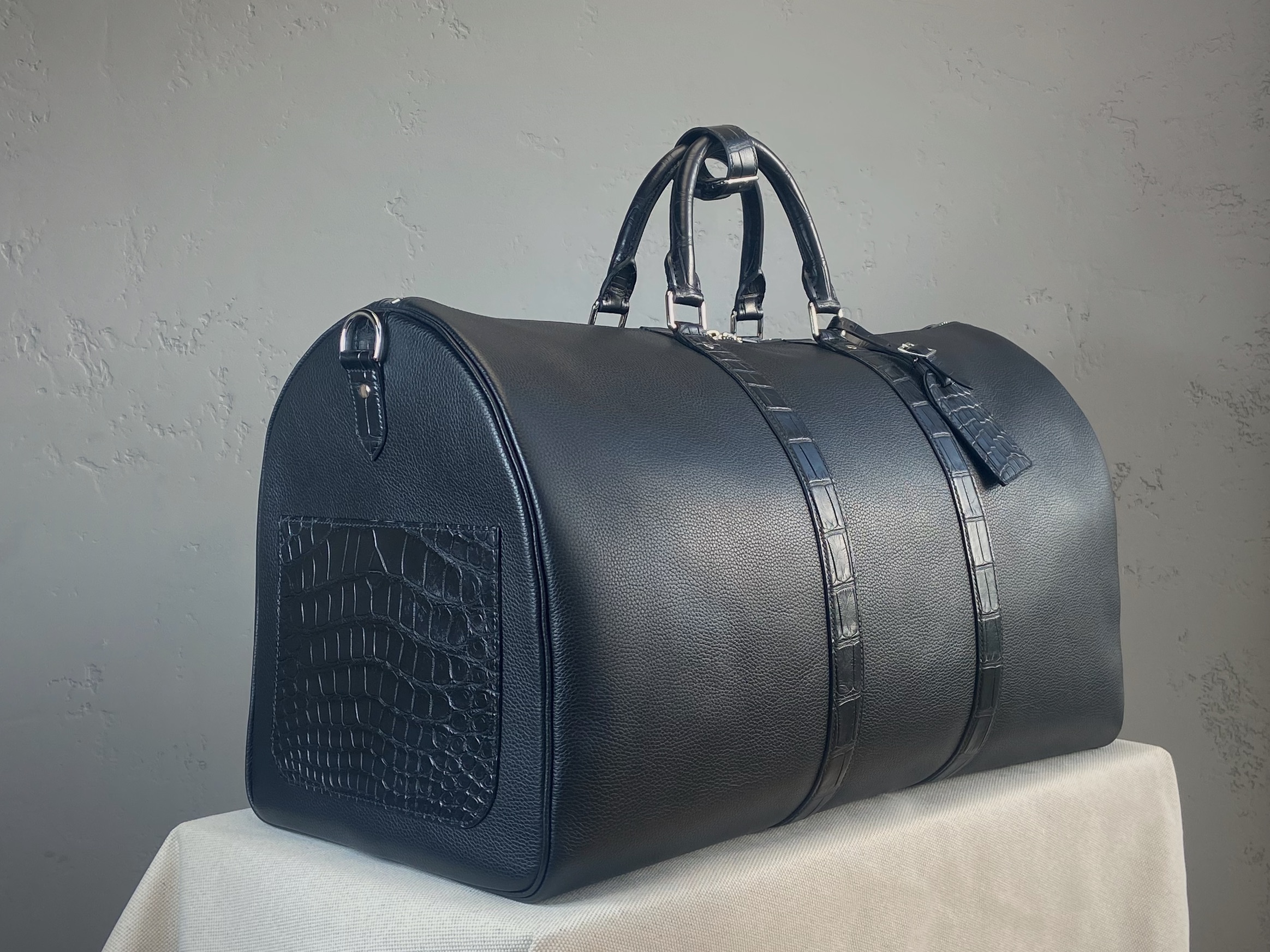 Side view of the bespoke travel bag in black calfskin and matte alligator leather