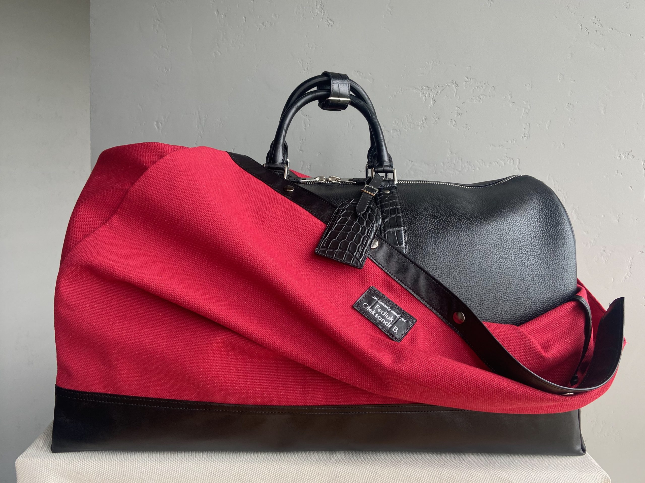 Bespoke travel bag partially covered by a custom red protective cover with alligator tag
