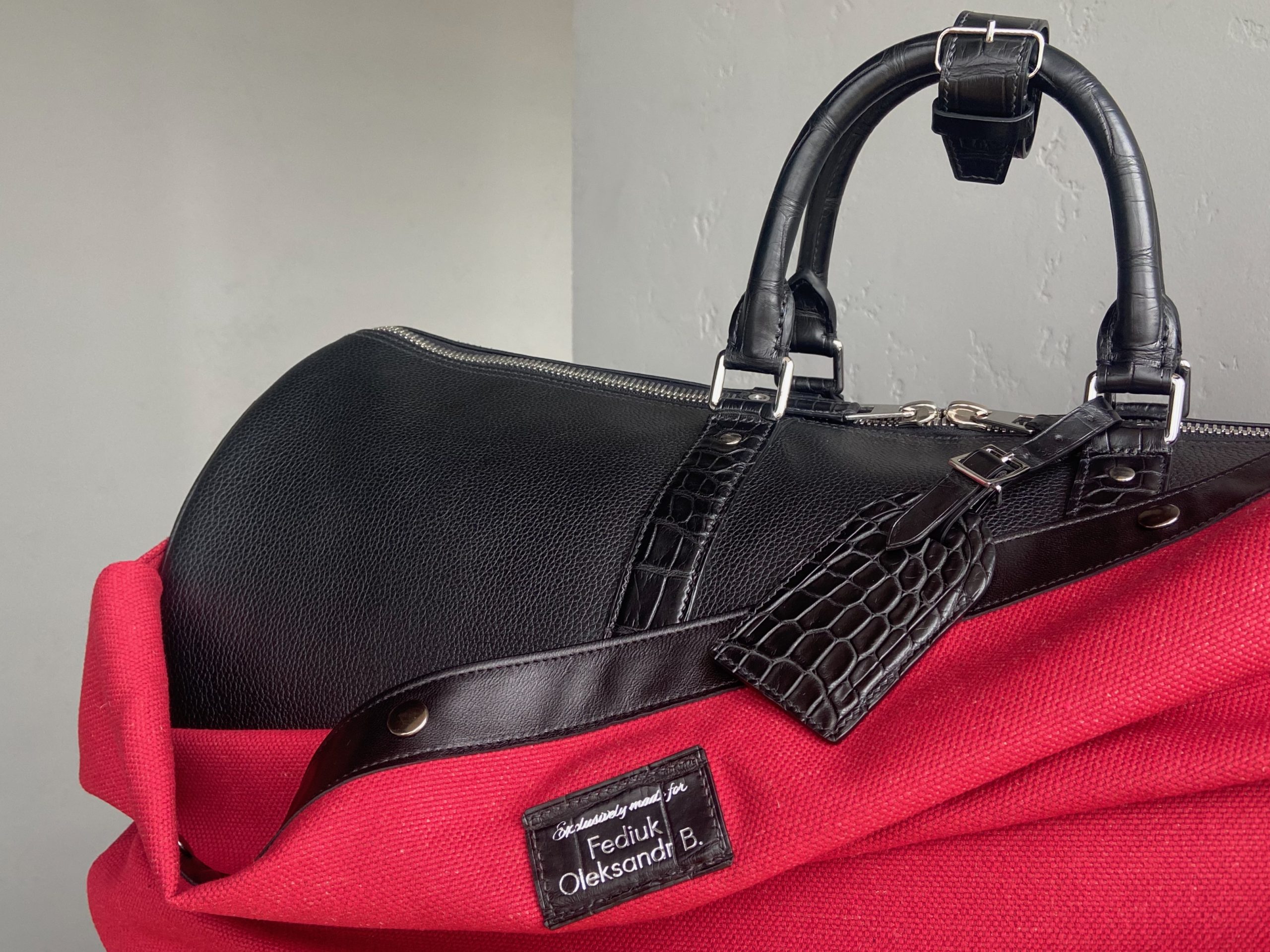 Close-up of the handles, alligator luggage tag, and personalized protective cover on a bespoke travel bag