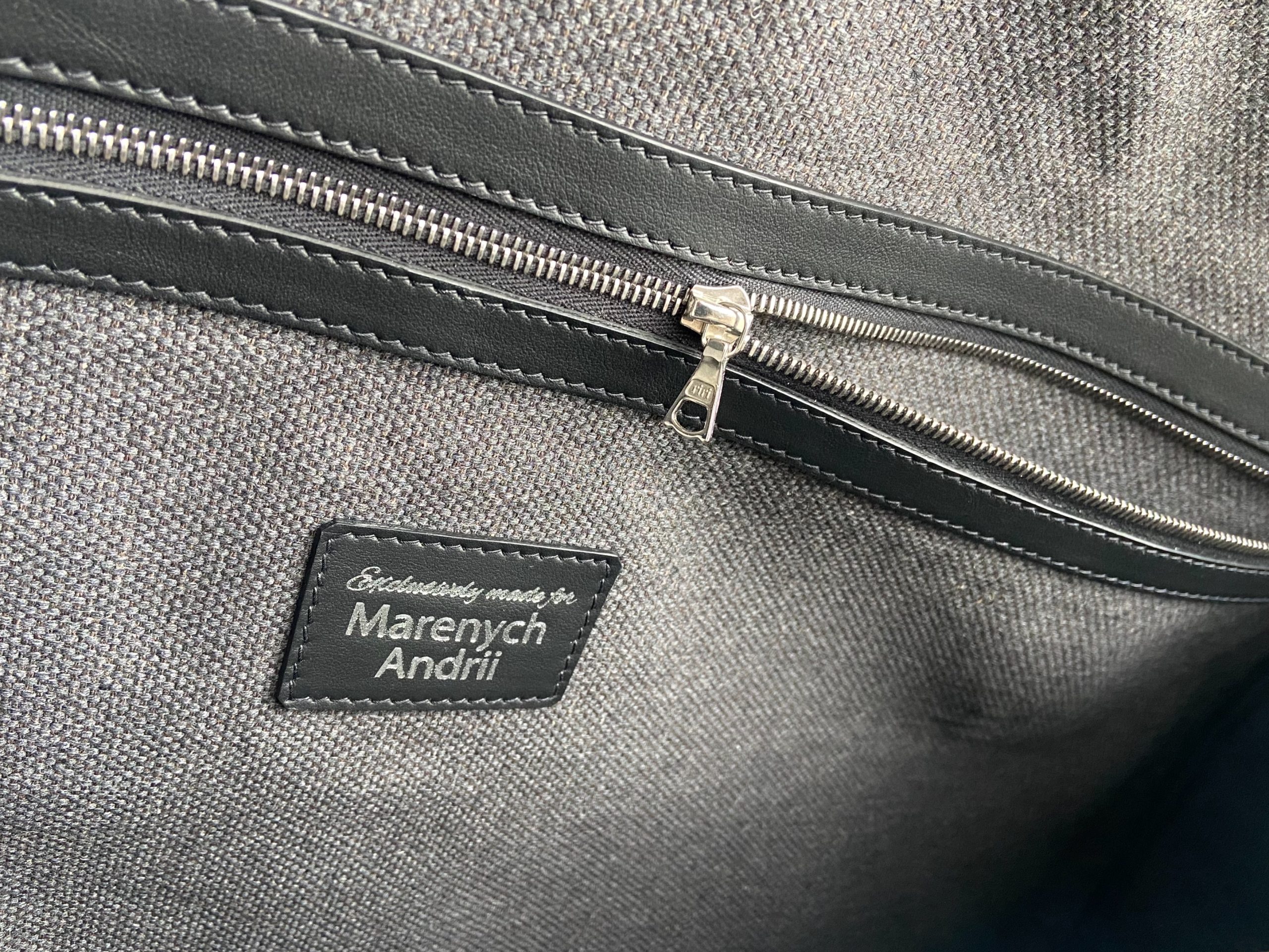 Interior name patch with embossed inscription "Exclusively made for Marenych Andrii" on a grey textile lining