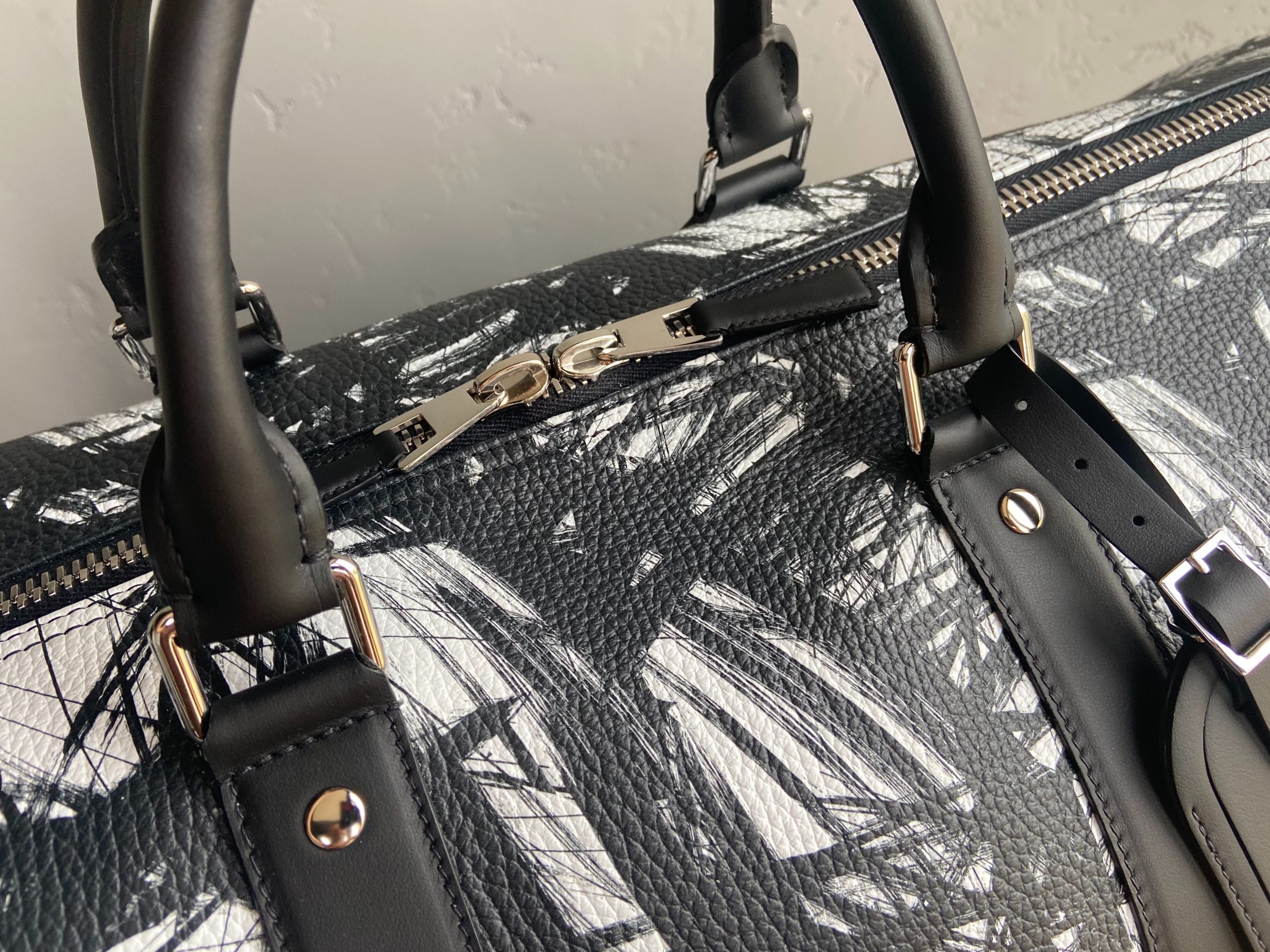 Close-up of leather travel bag handles and zipper closure with silver-tone hardware.
