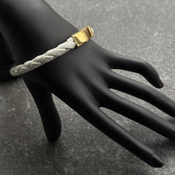 White braided calfskin bracelet with gold magnetic clasp on black hand display
