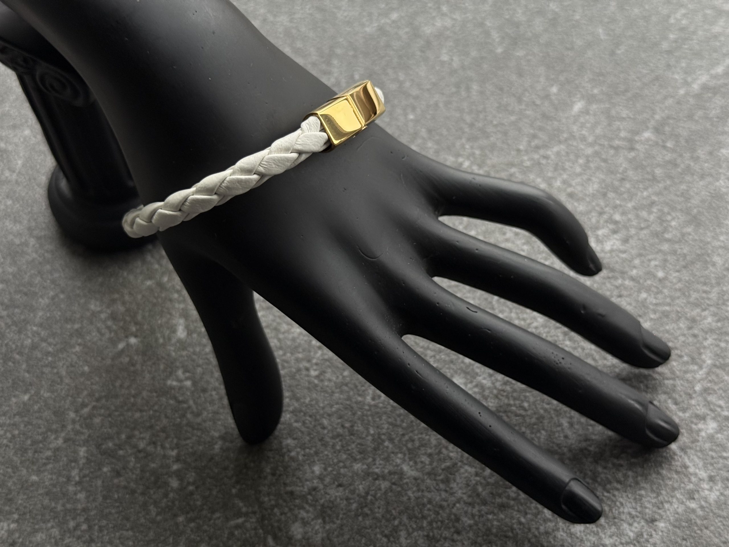 White braided calfskin bracelet with gold magnetic clasp on black hand display