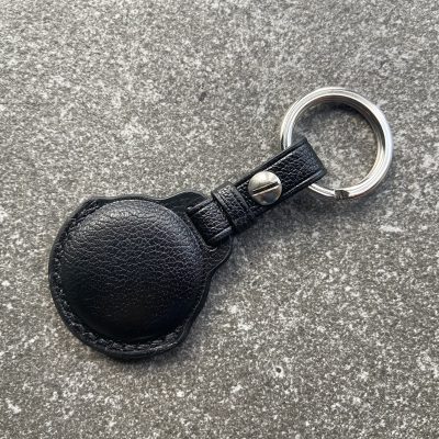 Leather keychain for Apple AirTag in black leather shown from the back on a stone surface