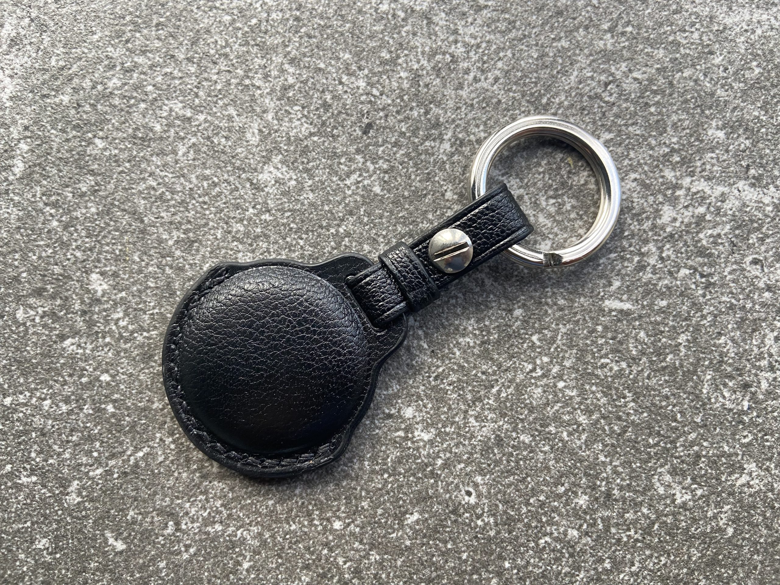 Leather keychain for Apple AirTag in black leather shown from the back on a stone surface