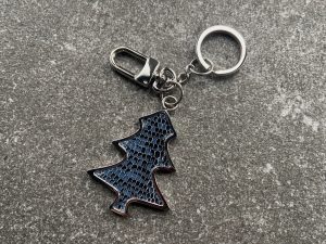 Key chain and bag charm with deep blue scaled texture on a stone surface