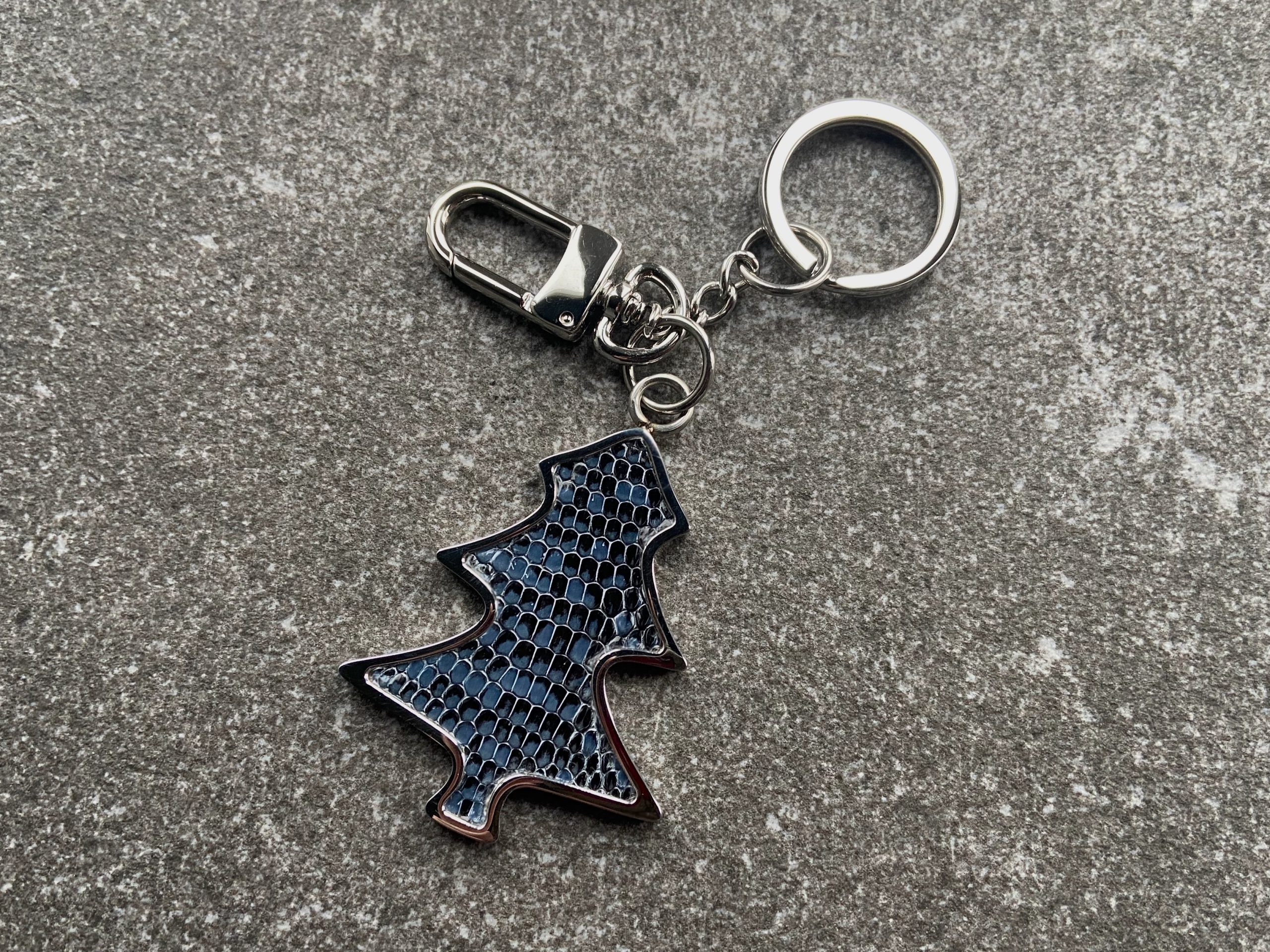 Key chain and bag charm with deep blue scaled texture on a stone surface