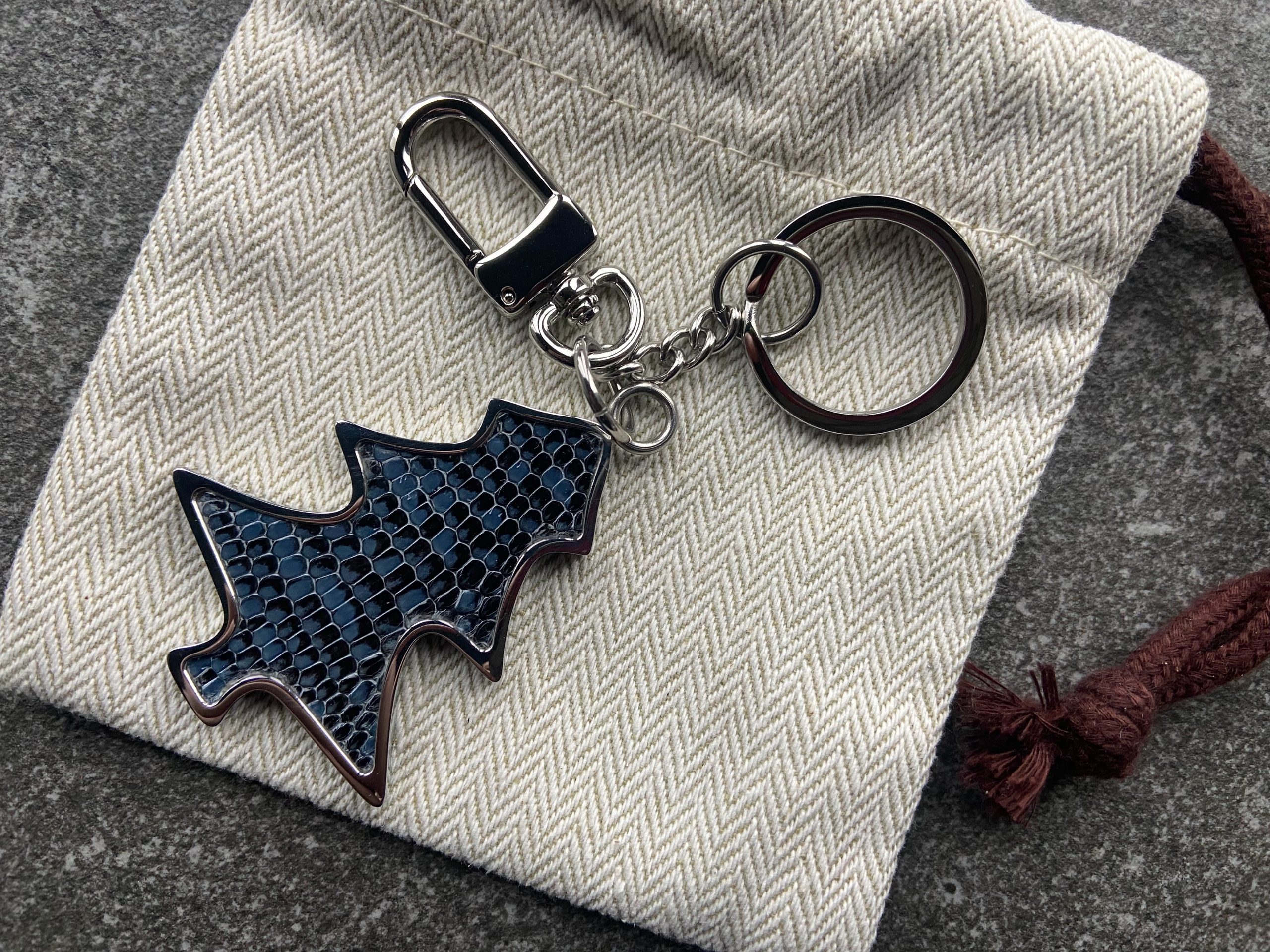 Key chain and bag charm with deep blue scaled texture placed on a fabric pouch