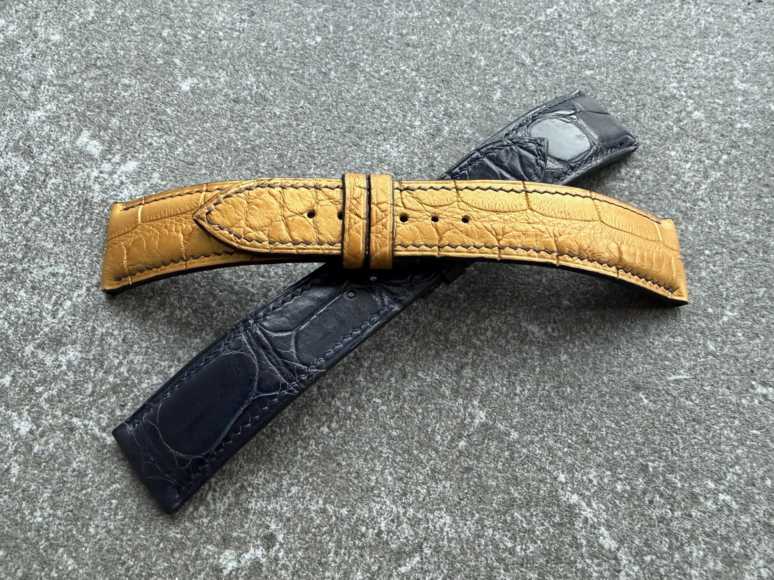 Front view of custom alligator leather watch straps for the Equilibrium project, showing the golden tone strap with a transverse cut and the deep blue strap beneath