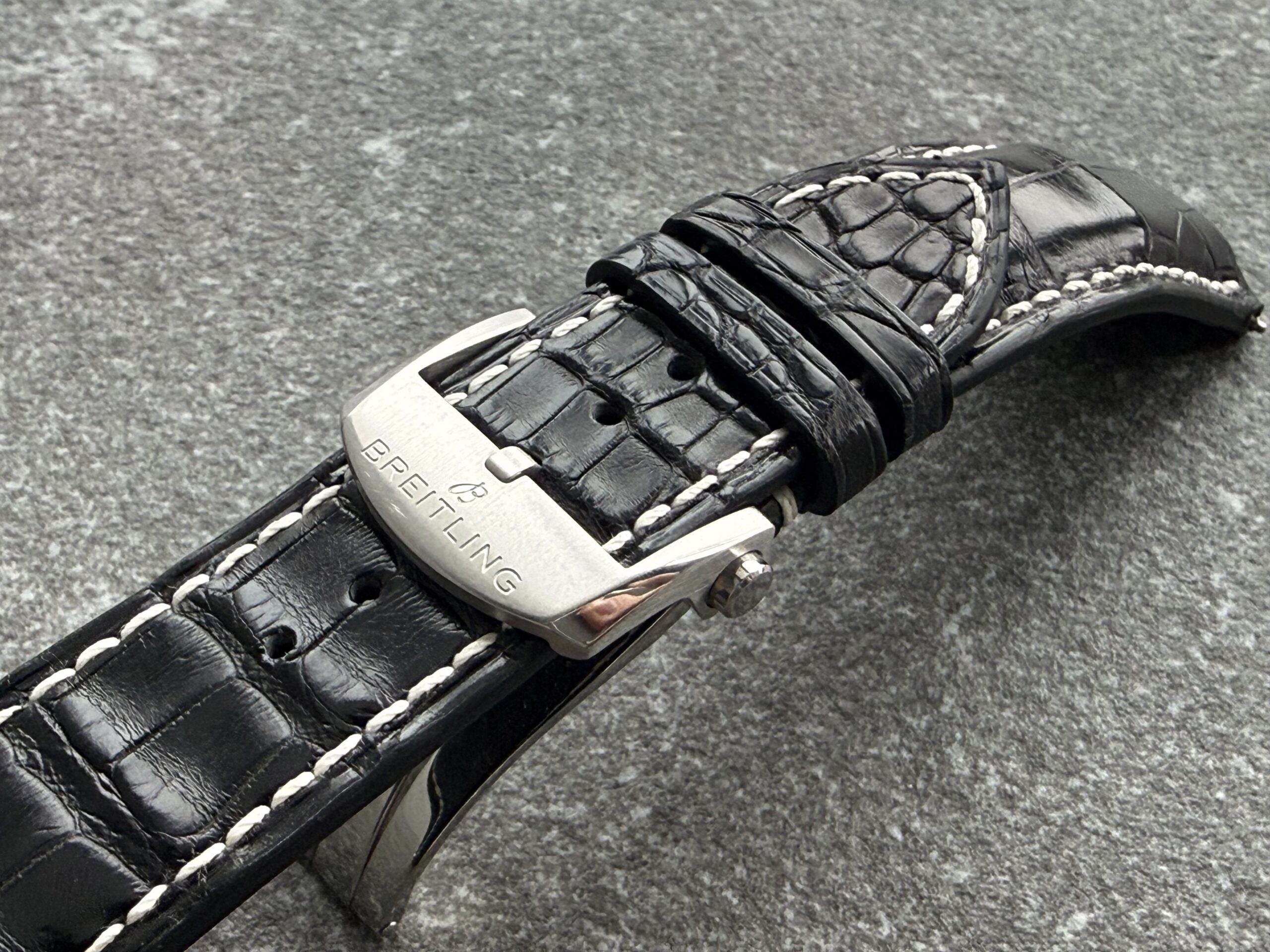 Close-up of black alligator strap for Breitling Avenger B01 with light contrast stitching and original Breitling clasp